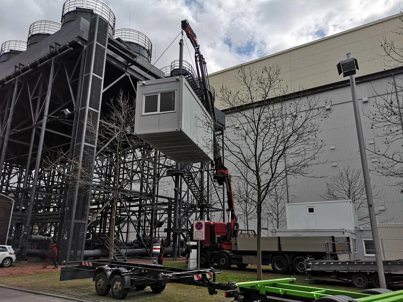 Ein mobiler Kran hebt einen Bürocontainer präzise an eine Industrieanlage – professionelle Montage durch erfahrenes Personal der Mobil-Raum GmbH im Einsatz.