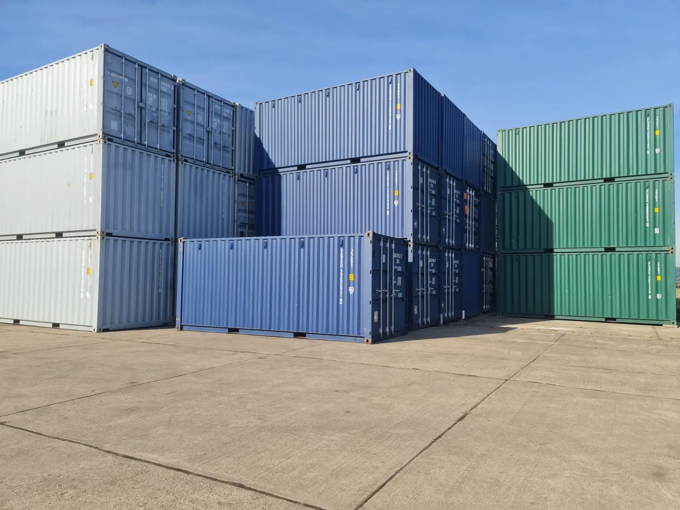 Gestapelte Lagercontainer in Blau, Grün und Grau auf einem Lagerplatz – ideal zur Miete oder zum Kauf für flexible Lagerlösungen im Außenbereich.