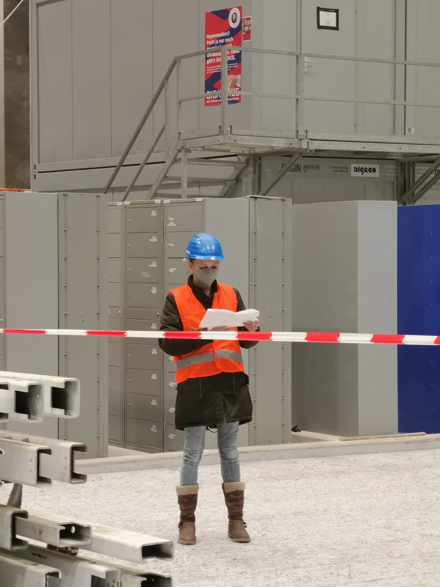 Eine Projektverantwortliche mit Warnweste und Bauhelm prüft Pläne auf einer Baustelle – unser Anspruch: durchdachte Containerlösungen mit persönlichem Einsatz.